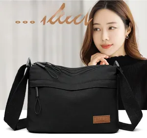 Detail view of the black waterproof nylon crossbody bag with multi-layer zipper compartments