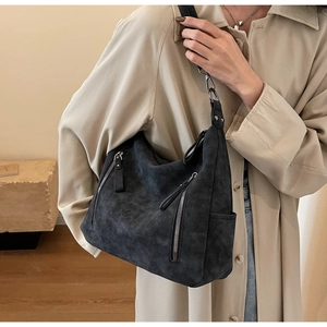 Detail of matte black leather hobo bag with silver zipper accents and wide strap