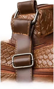 Macro shot of silver metal strap buckle and adjustable buckle on brown woven leather bag
