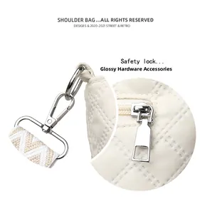 Detail of glossy silver hardware and safety lock on quilted beige crossbody bag