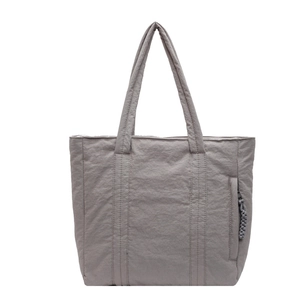 Grey quilted tote bag with dual handles and side zipper pocket on a white background