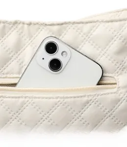 Detail view of cream quilted shoulder bag featuring external zipper pocket for smartphone