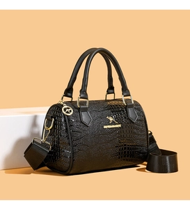 Détail du sac à texture crocodile noire avec logo kangourou doré et bandoulière large