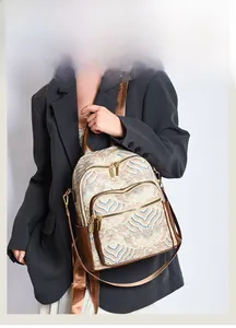 Detail of vintage patterned backpack with brown leather trim and golden hardware