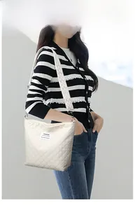 Detail of quilted beige shoulder bag with geometric strap and fashion label patch