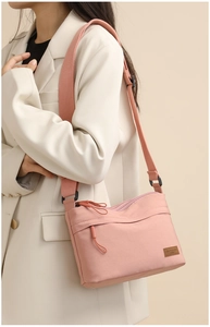 Detail of pink nylon crossbody bag with leather logo patch and adjustable wide strap