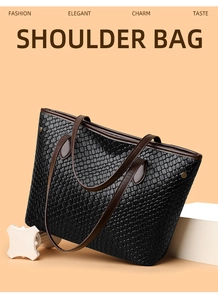 Detail of black woven shoulder bag with brown strap on a warm orange background