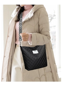 Detail of quilted rhombic shoulder bag featuring a geometric black and white wide strap