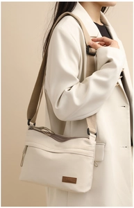 Detail showing beige nylon crossbody bag with brown wide strap and SOSIDI logo tag