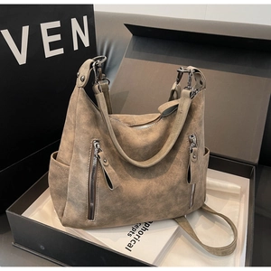 Detail view of large khaki tote bag featuring matte texture and functional dual front zippers
