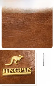 Close-up of brown lychee grain leather texture and golden kangaroo hardware logo