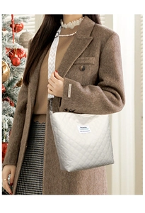 Detail of white quilted tote bag with diamond pattern and adjustable crossbody strap