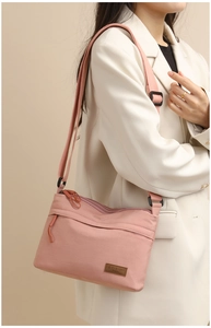 Detail of pink nylon crossbody bag with adjustable strap and multiple zipper pockets