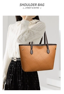 Detail of brown textured tote bag with woven pattern and gold hardware on shoulder