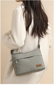 Detail of the grey nylon crossbody bag with premium SOSIDI leather logo and front pocket