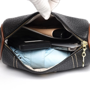 Sac bandoulière en cuir noir grande capacité montrant l'espace de rangement interne avec objets