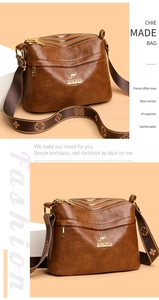 Close-up of brown faux leather crossbody bag with three zipper compartments and wide strap