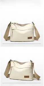 Detail view of cream nylon crossbody bag with dual zipper compartments and leather logo