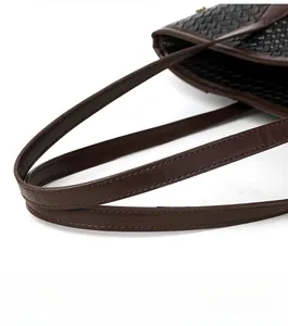 Detail of woven black tote bag with premium brown leather strap and reinforced stitching