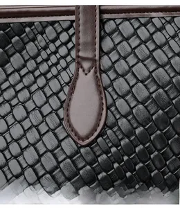 Detailed close-up of woven black leather texture with brown stitched handle seams