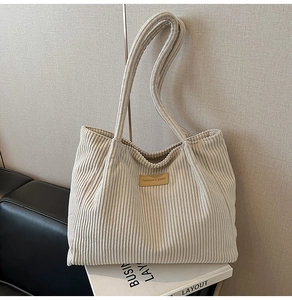 Détail du sac fourre-tout en velours côtelé avec étiquette en cuir sur tissu beige