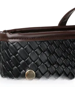 Detail of hand-woven black leather tote with brown trim and gold metal rivet detail