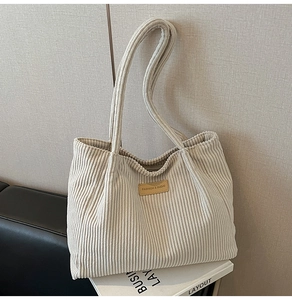 Détail du cabas en velours côtelé crème avec texture verticale et écusson mode