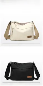 Detail view of multi-pocket nylon shoulder bag with wide strap and branded leather patch