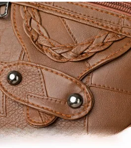 Close-up of brown litchi textured leather bag with woven details and metal rivets