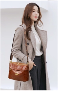 Close-up of brown crocodile texture bag with golden logo and patterned wide strap