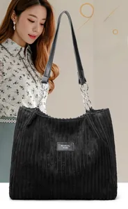 Detailed shot of large black corduroy tote bag with chain strap and stitched brand logo