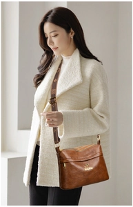 Detail of caramel brown crossbody bag with kangaroo logo and vintage patterned strap