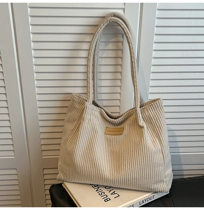 Détail du cabas en velours côtelé beige avec un écusson en cuir sur le tissu de qualité