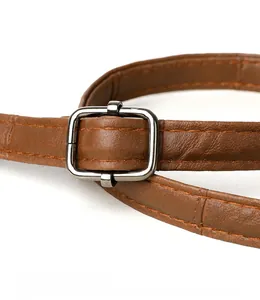 Detail of brown leather bag strap with matte silver buckle and precision stitching