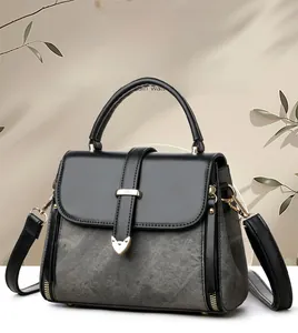 Detail of grey textured crossbody bag featuring a golden heart lock and black leather handle