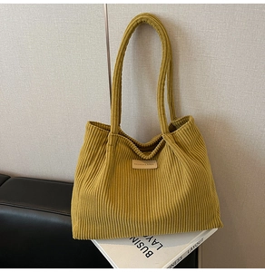 Détail d'un cabas en velours côtelé jaune moutarde avec un écusson de logo cousu
