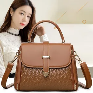 Detail of brown leather handbag featuring woven texture and gold metal buckle hardware