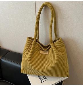 Détail macro du sac cabas en velours côtelé jaune moutarde avec écusson en cuir mode