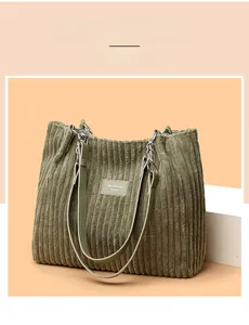 Close-up of sage green corduroy tote bag featuring chain straps and a brand logo tag