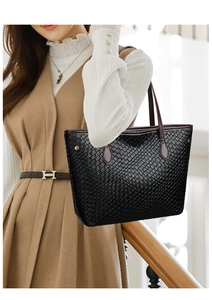 Detail showing black woven tote bag with diamond pattern and brown leather straps