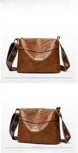 Detail of brown leather crossbody bag featuring multiple zippers and jacquard strap