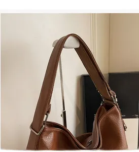 Details einer dunkelbraunen Ledertasche mit Textur und silberner Metallschnalle