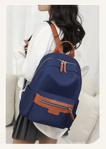 Detail of blue nylon backpack with brown leather trim showing side pockets and zippers