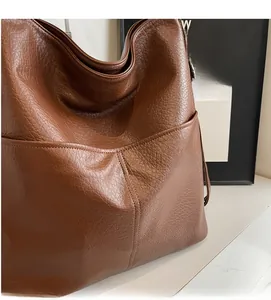 Detailaufnahme der karamellbraunen Totebag mit feiner Ledernarbung und funktionaler Seitentasche