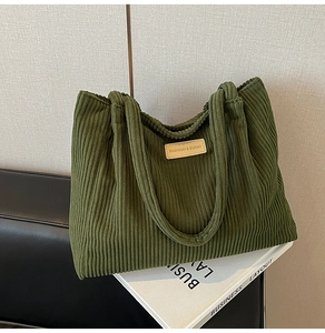 Detail of green corduroy tote bag showing vertical texture and tan fashion logo patch