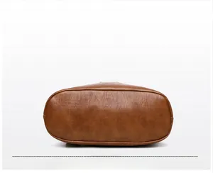 Detail view of the brown leather bag base showing smooth stitching and oval structure