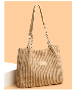 Detail of corduroy tote bag featuring beige leather strap and silver metal chain link