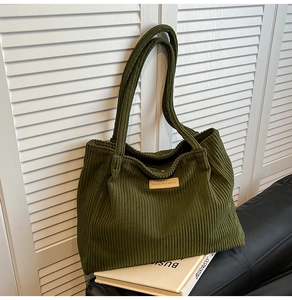 Gros plan sur un sac cabas en velours côtelé vert foncé avec texture rayée et logo cuir