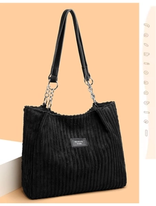 Detail of black corduroy tote bag featuring leather metal chain and brand logo patch