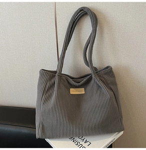 Détail d'un sac cabas en velours côtelé gris foncé avec écusson logo et texture